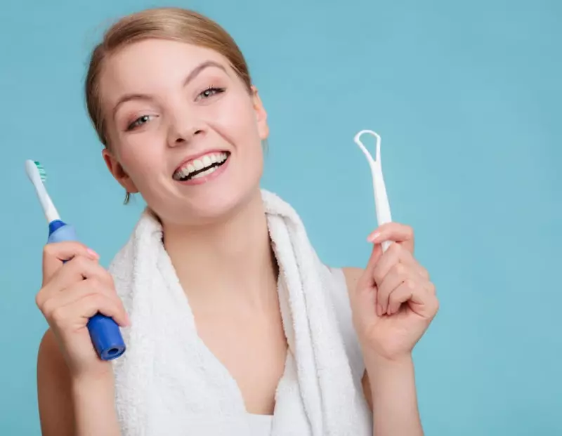 woman holding tongue scraper and toothbrush